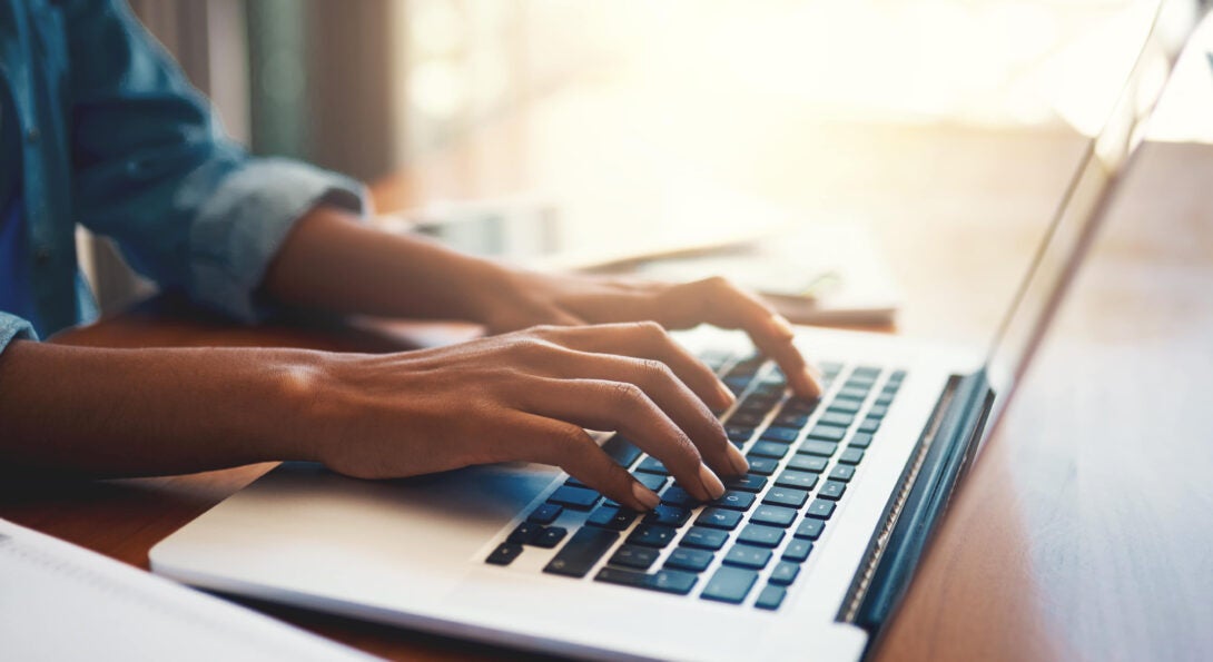 Hands typing on a laptop keyboard