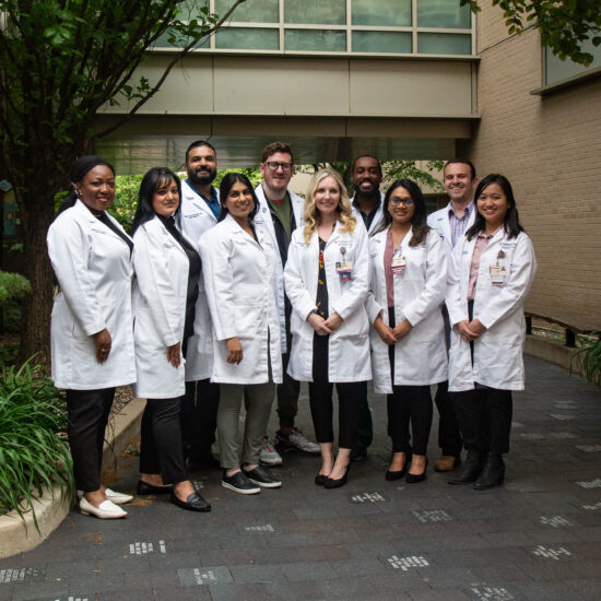 A group of graduates posing and smiling in white coats