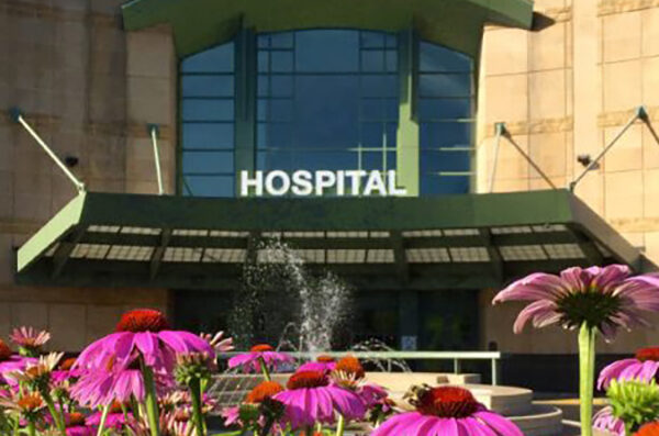 Building entrance labeled Hospital with pink flowers in the foreground