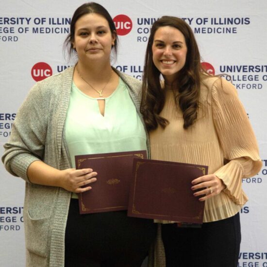 Two women pose for photo, holding certificates.