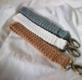 Three crocheted keychains in tan, white and blue on white fabric