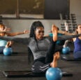 Fit woman with outstretched arms and legs balancing on a blue ball